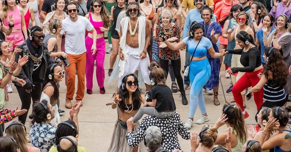 People gather outside in an urban space for a Daybreaker morning dance party.