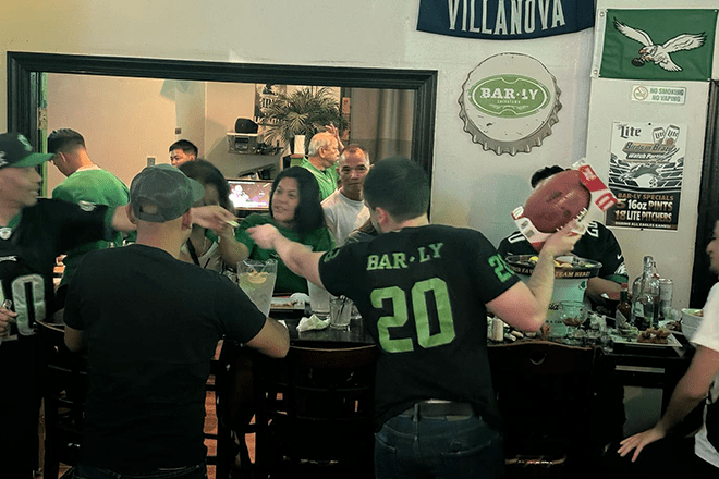 Bar-Ly, a taproom in Chinatown, hosts regular Eagles game day specials. Here, people wearing Bar-Ly and Eagles gear are in the bar.