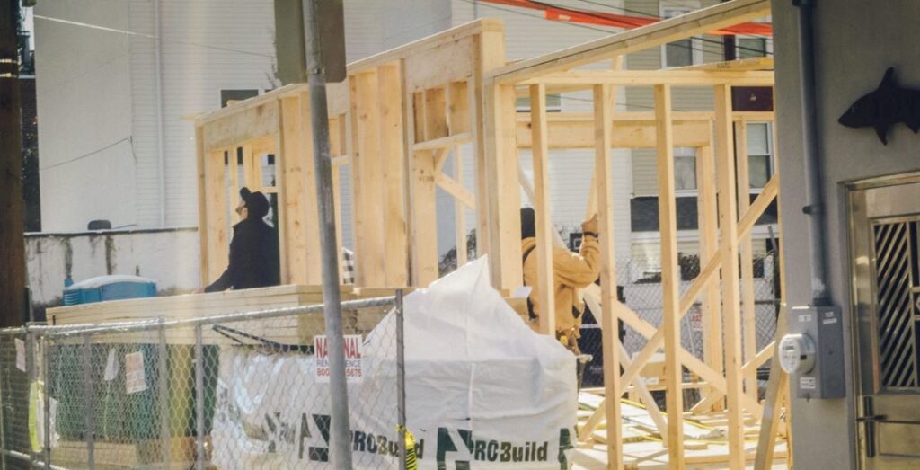 Construction workers assemble wood framing on a house under construction