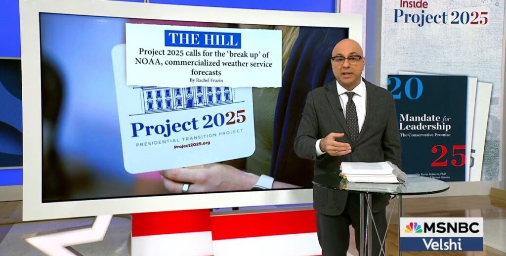 Show host Ali Velshi, a bald man with glasses in a grey suit and light blue shirt, stands beside a large monitor showing headlines about Project 2025 and FEMA.