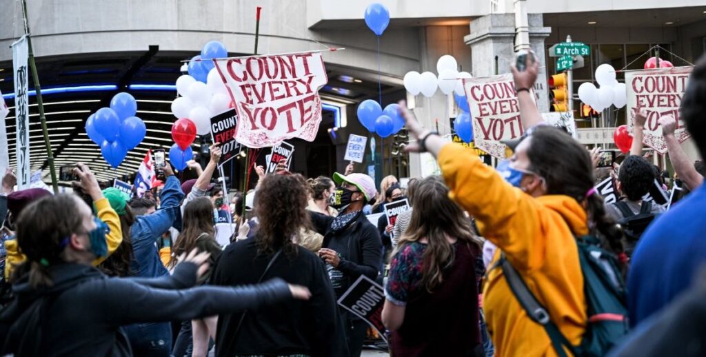 A crowd of masked men, women, and youth are gathered in front of Philadelphia's Pennsylvania Convention Center at 12th and Arch Streets on November 5, 2020, demonstrating to keep the ballot counting going