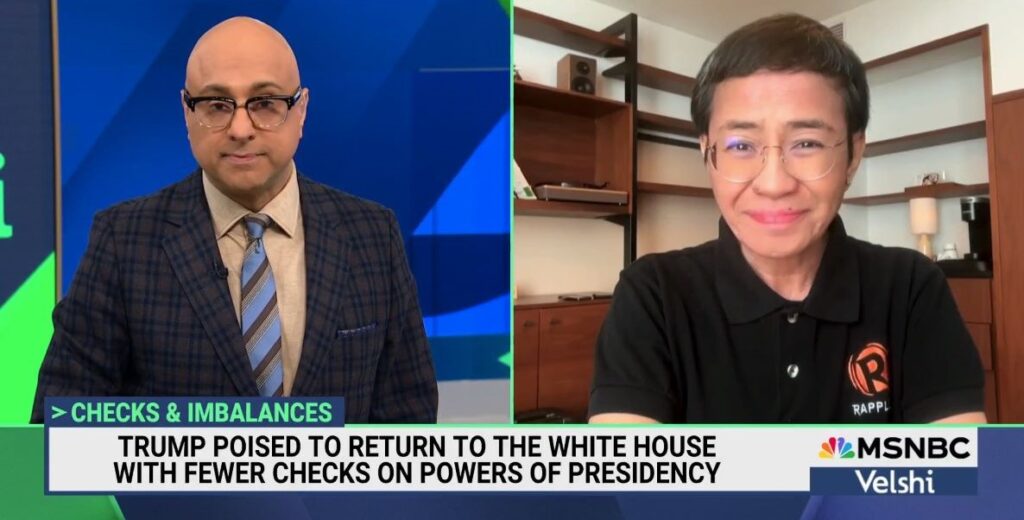 On the left, a bald man wearing glasses dressed in a brown plaid suit jacket and blue striped tie is interviewing a Philippine woman on the right with short hair, frameless round glasses and a black t-shirt