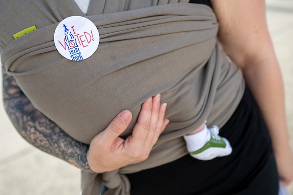 Victoria Boyer swaddles her one-month old as she hands out literature as a Democratic Committee Person outside South Philadelphia High School. By Sabina Louise Pierce.