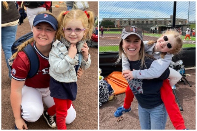 At left a young softball player in her Penn team uniform crouches beside a young girl with pigtails glasses and red pants. At right, another young woman carries the same child on her back