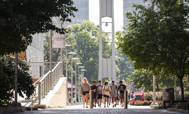 Students walk outside on Temple's campus in warm weather. 