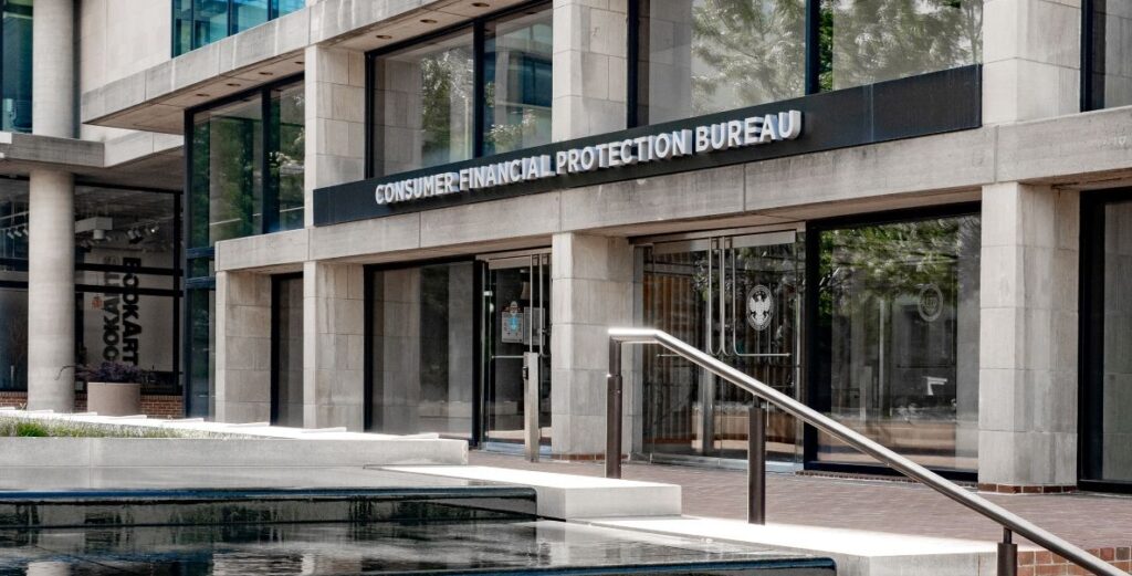 The concrete squared column and large glass window facade of the Consumer Financial Protection Bureau in Washington DC as seen from the stairs on the plaza in front of the building