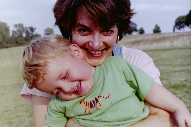 Suzanne Simonelli, a white woman with short brown hair, holds a toddler with blonde hair wearing a shirt with a tiger on it. Both smile. They are in Valley Forge.
