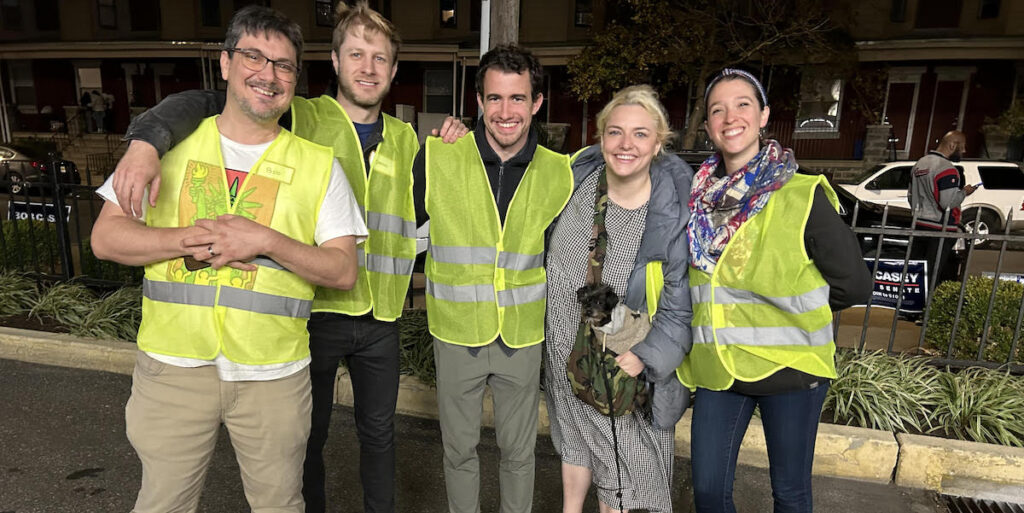 Three men and two women — four in reflective vests — pose outdoors in Philadelphia. They are volunteers for Changing the Conversation Together, a deep canvassing group that works in West Philadelphia.