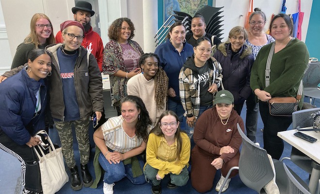 A diverse group of adults stand and squat for a classroom photo. They are the staff of Historic Fair Hill.