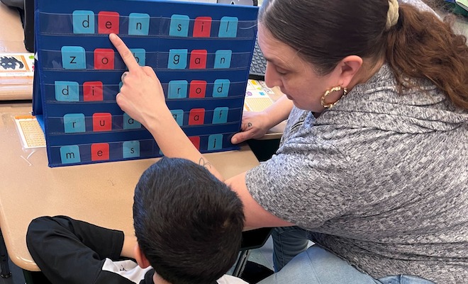 Literacy assistant Ms. Angie working with a student at Julia de Burgos Elementary.