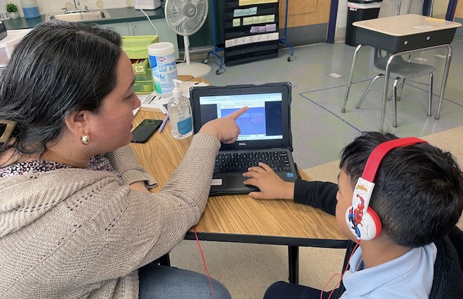 A literacy assistant Ms. Tassie working with a student at Julia de Burgos Elementary.