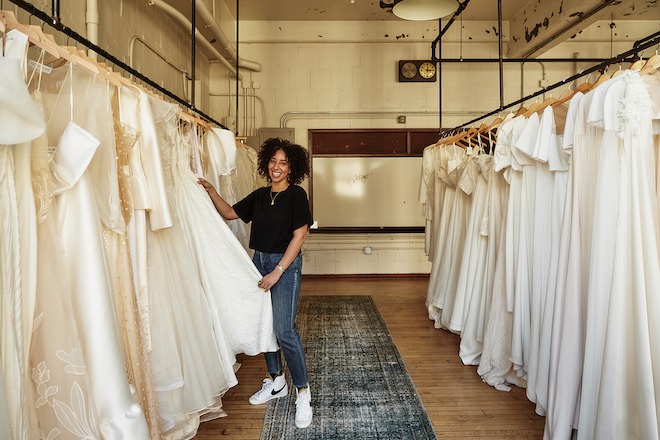 Mayana Carter, owner of Kinfolk Bride, stands among bridal gowns.